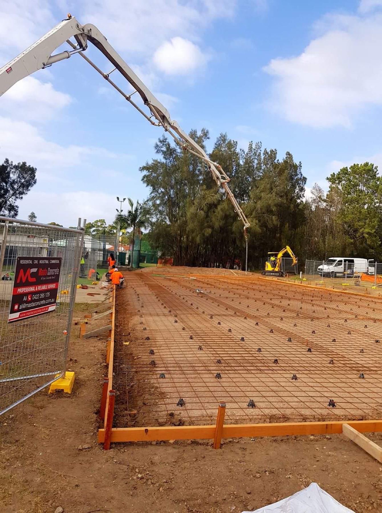 Concrete pump pouring a large reinforced civil pad behind Masta Concrete site fencing in Sydney