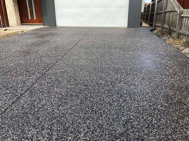 Charcoal exposed aggregate concrete finish with sawcut joints showing surface texture