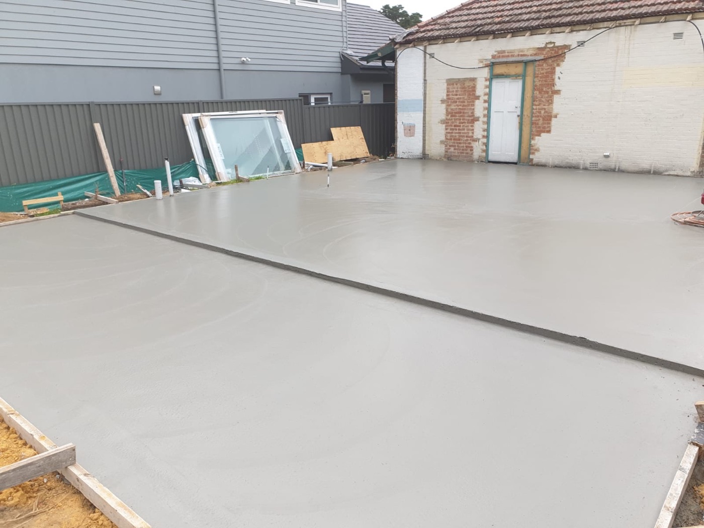 Freshly poured smooth concrete shed and garage slab in a Sydney backyard
