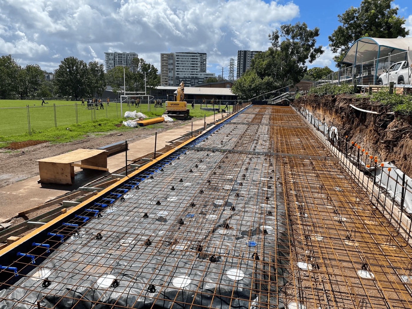 Engineered residential slab with steel reinforcement laid across bearers on a Sydney site — excavator in background